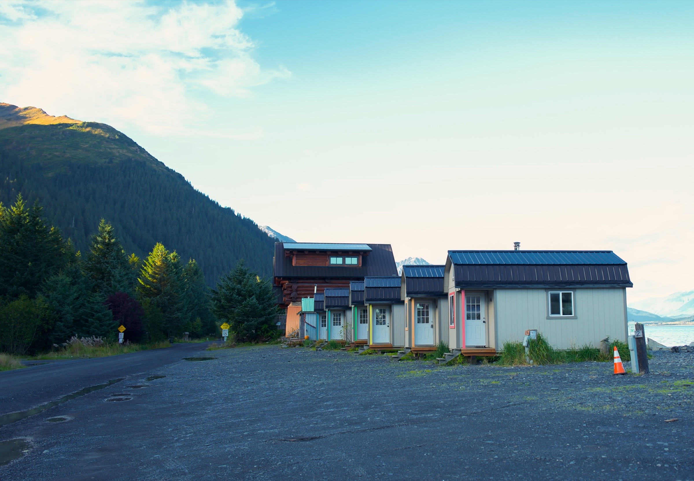 Small cabins at the edge of mountains and water in Alaska.