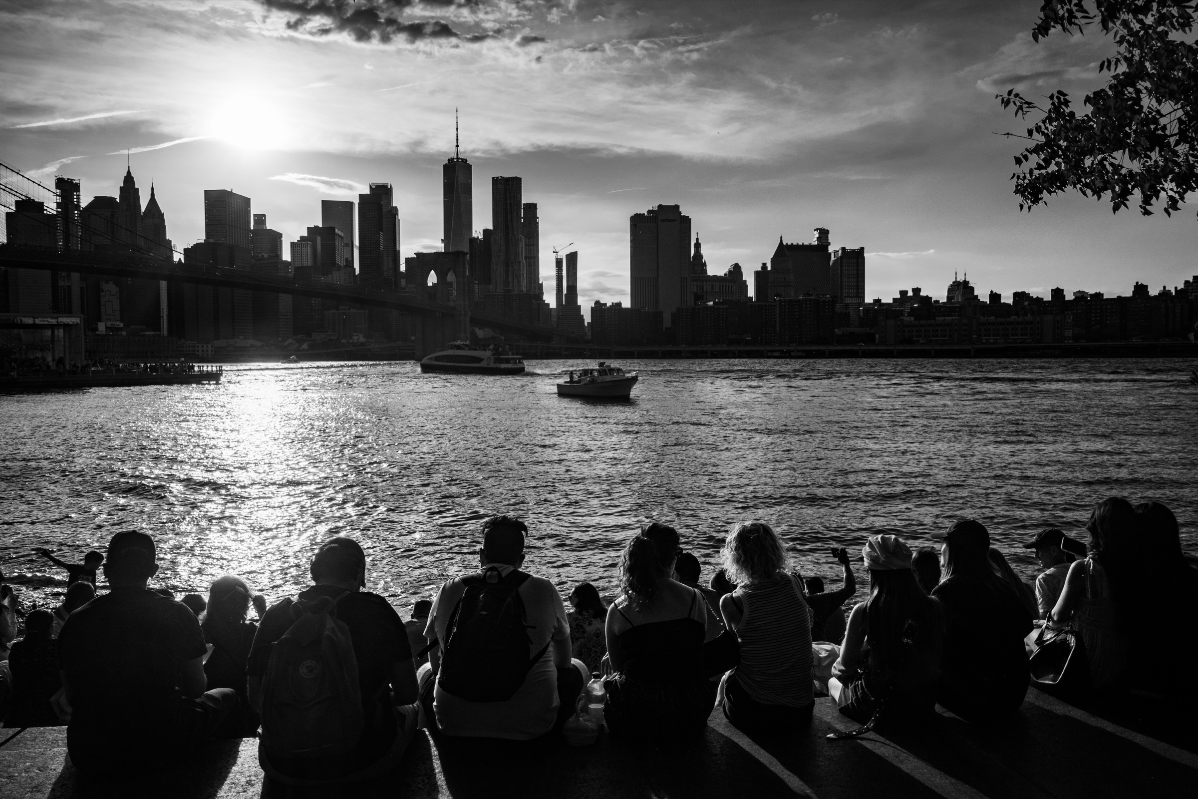 Black and white New York skyline with people by the water.