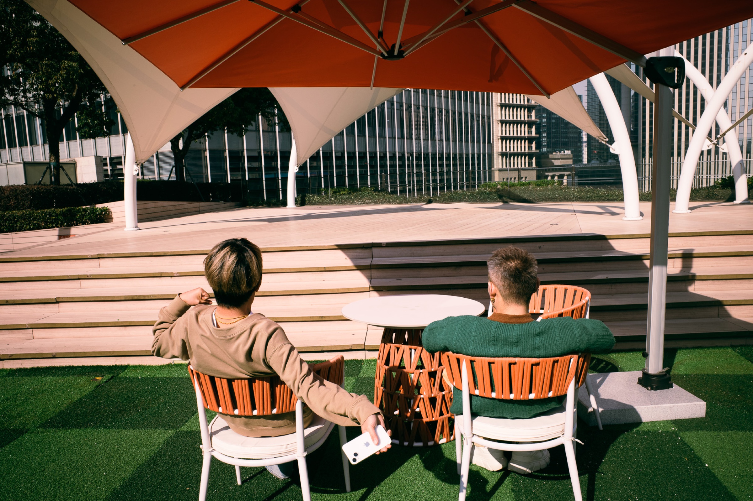 Two people sitting under an orange umbrella in Shanghai.